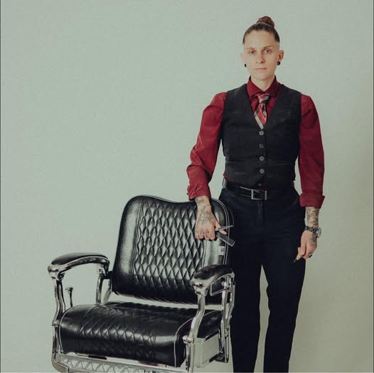 Nae, award-winning barber at The Edge Barbershop in Linton Indiana, standing next to a classic barber chair